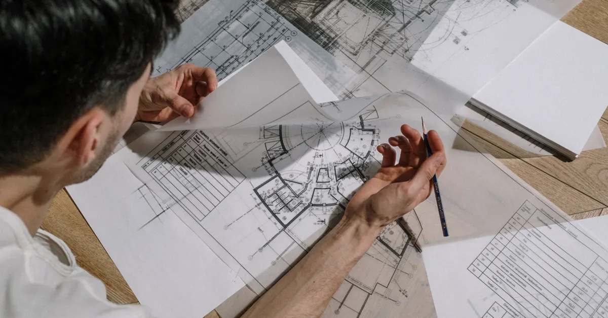 Reviewing a technical drawing at a desk before defining a Revit family's parameters