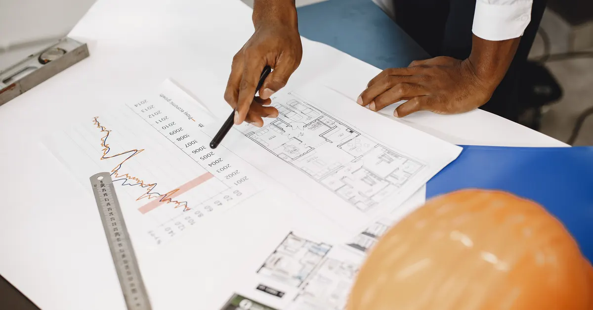 Reviewing a floor plan and a chart on a desk, standing in for the three different shapes of Revit plugin work